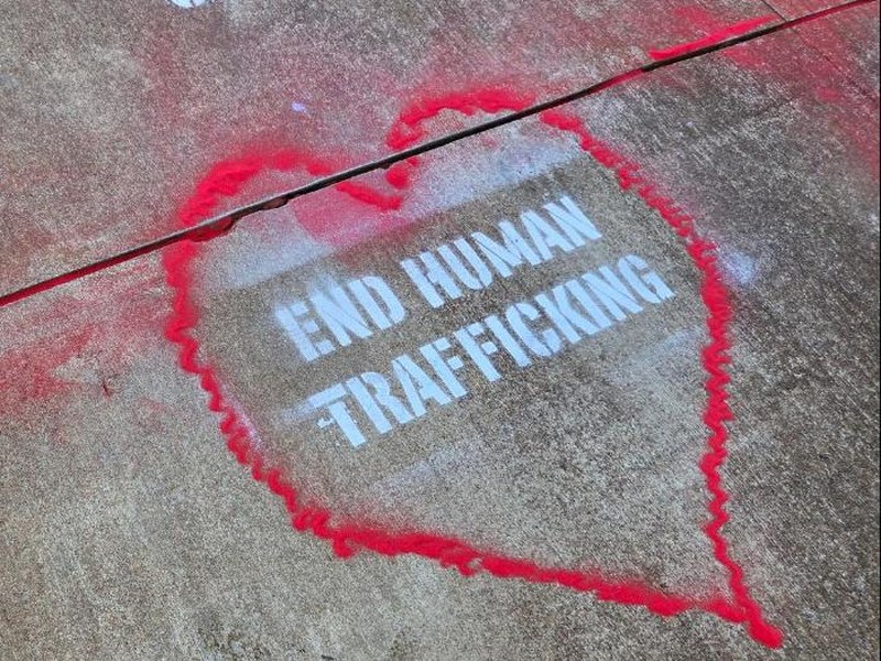 Red sand heart outlining a stenciled End Human Trafficking message on a sidewalk, from the Red Sand Project in Nags Head
